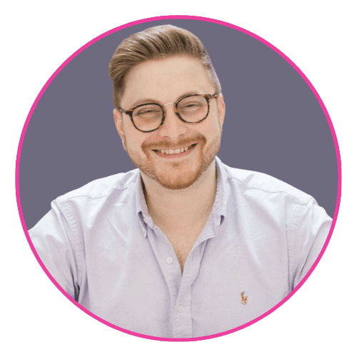 Joseph smiling, wearing round glasses and a light purple button-up shirt with a small embroidered logo.