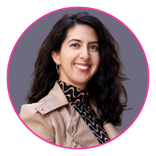 Catarina smiling, wearing a beige jacket over a black top with a wavy beige pattern.