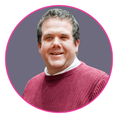 Robbie smiling slightly against a grey background, wearing a maroon sweater over a white shirt.