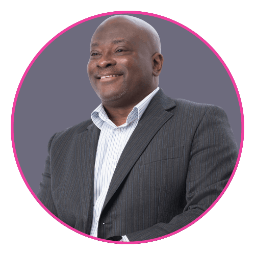 Dr Mark Esho smiling, wearing a dark pinstripe suit jacket over a light striped shirt.