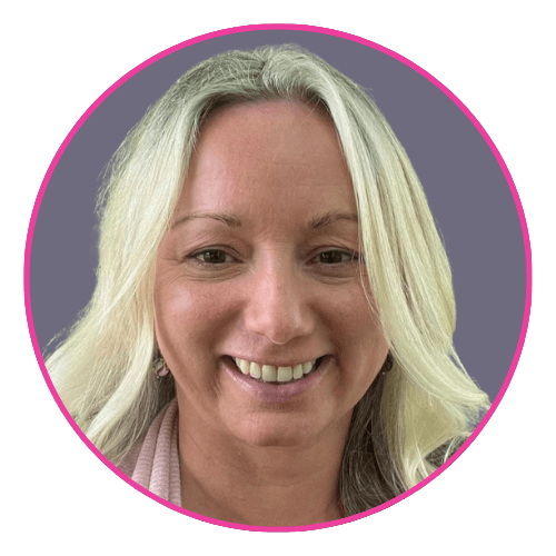 Mary smiling, wearing a light pink top and small earrings, with long light blonde hair.