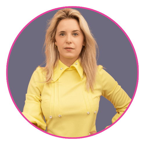 Brooke smiling, wearing a yellow long-sleeved top with decorative buttons and pleats.