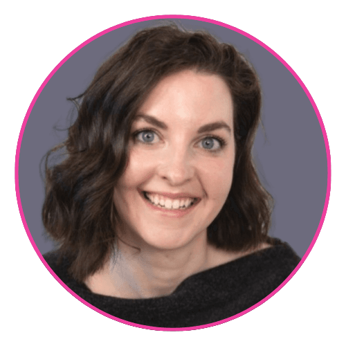 Julie smiling against a grey background, wearing a dark off-the-shoulder top.