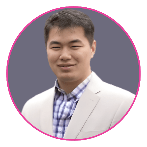 Ben wearing a light blazer over a blue and white checkered shirt, seated against a grey background.
