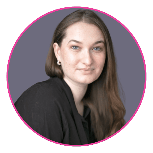 Rachael looking left against a muted purple background, wearing a black top and hoop earrings. 
